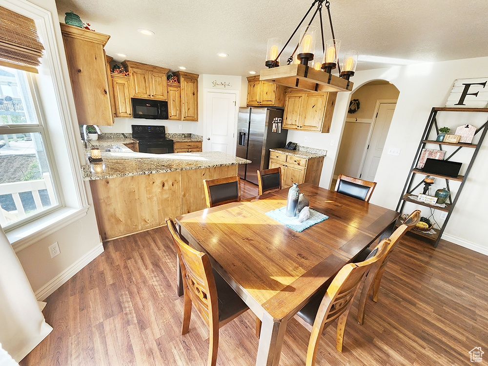 Dining space with arched walkways, light wood-type flooring, and recessed lighting