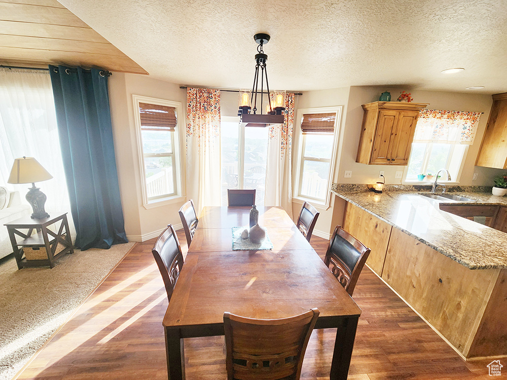 Dining room with a textured ceiling, dark wood-style floors, and a chandelier