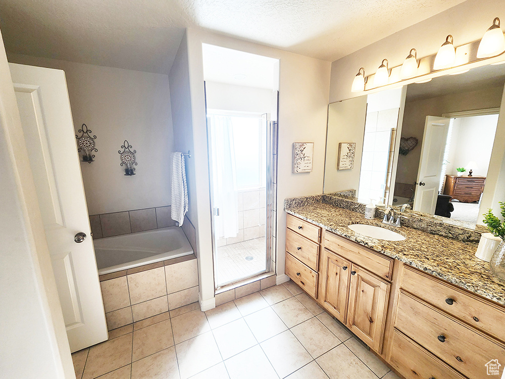 Bathroom featuring vanity, a garden tub, a stall shower, tile patterned flooring, and a textured ceiling