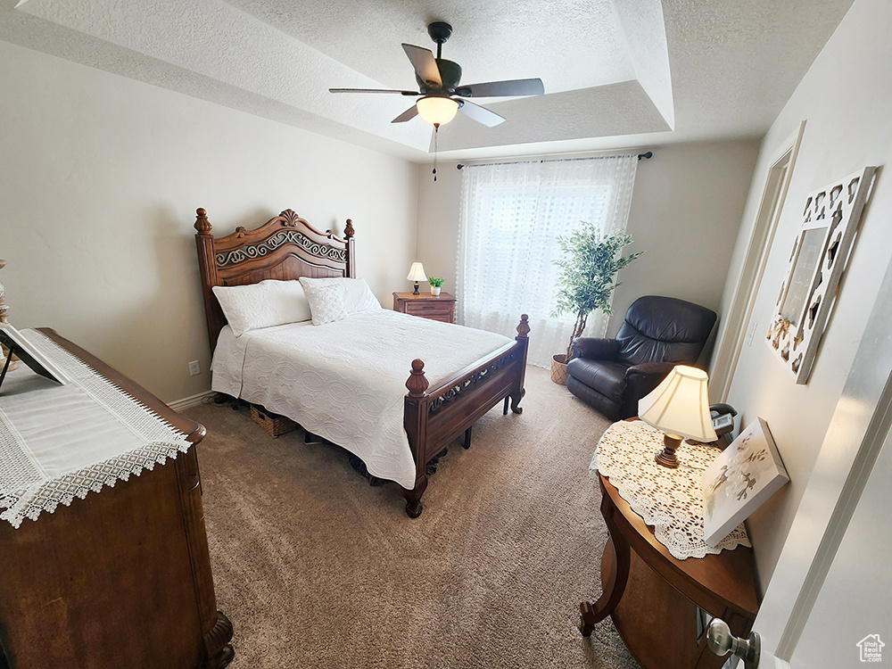 Bedroom featuring a textured ceiling, carpet floors, and ceiling fan