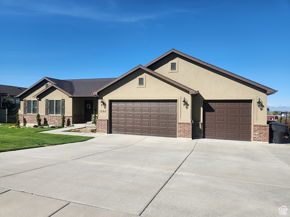 Ranch-style house with brick siding, a garage, concrete driveway, and stucco siding