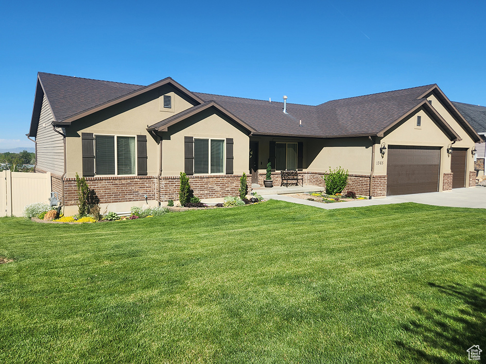 Single story home featuring brick siding, an attached garage, driveway, and stucco siding