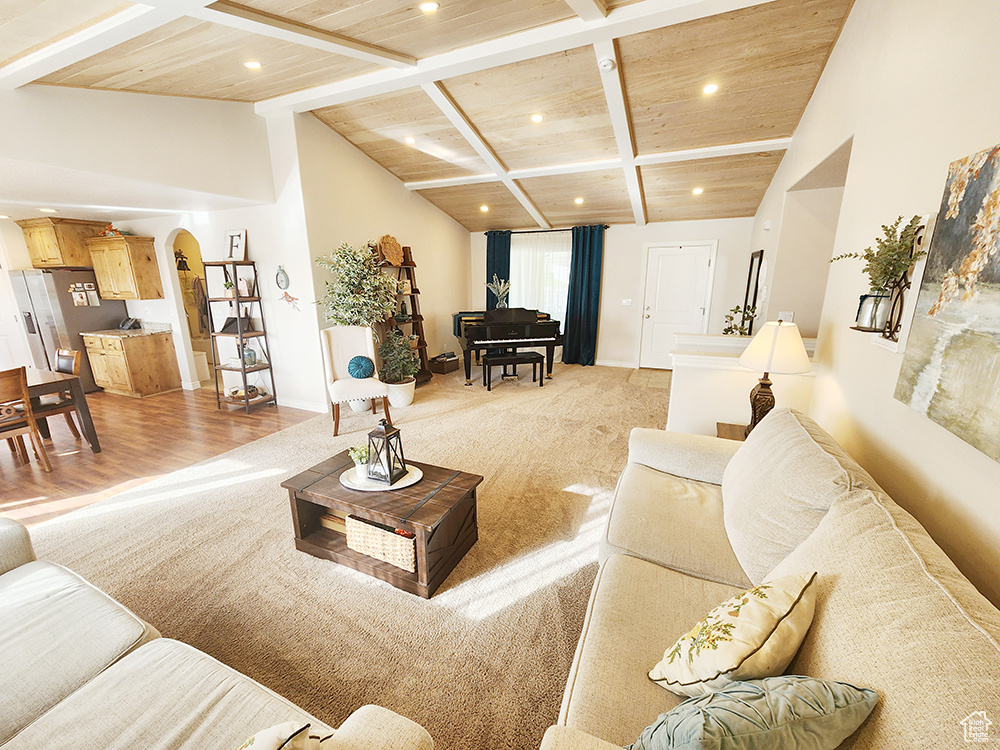Living room featuring wooden ceiling, arched walkways, recessed lighting, and light carpet