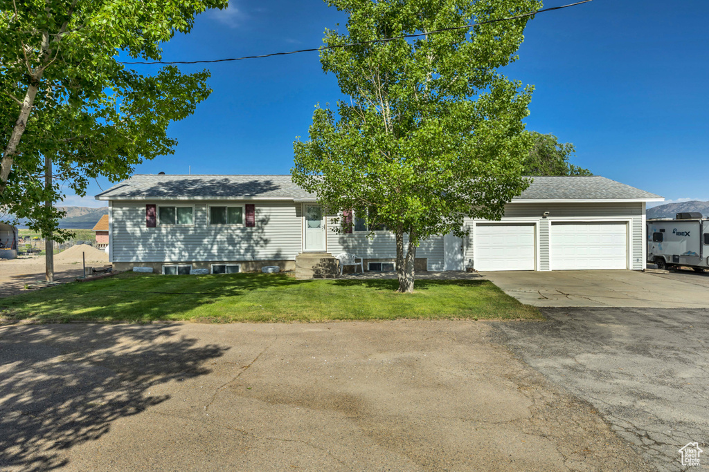 View of front of home featuring driveway, entry steps, an attached garage, a front lawn, and a shingled roof