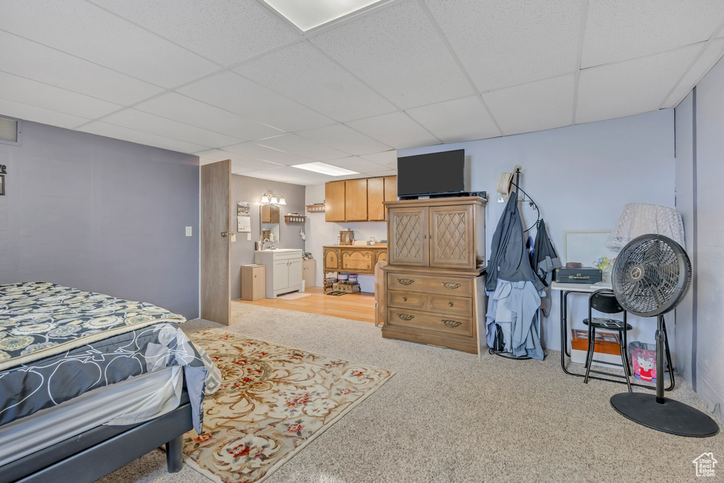 Bedroom with a paneled ceiling, ensuite bathroom, and light carpet