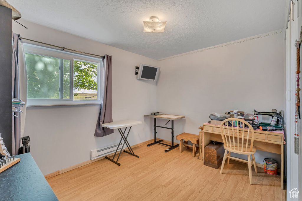 Misc room with wood finished floors, a textured ceiling, and a baseboard radiator
