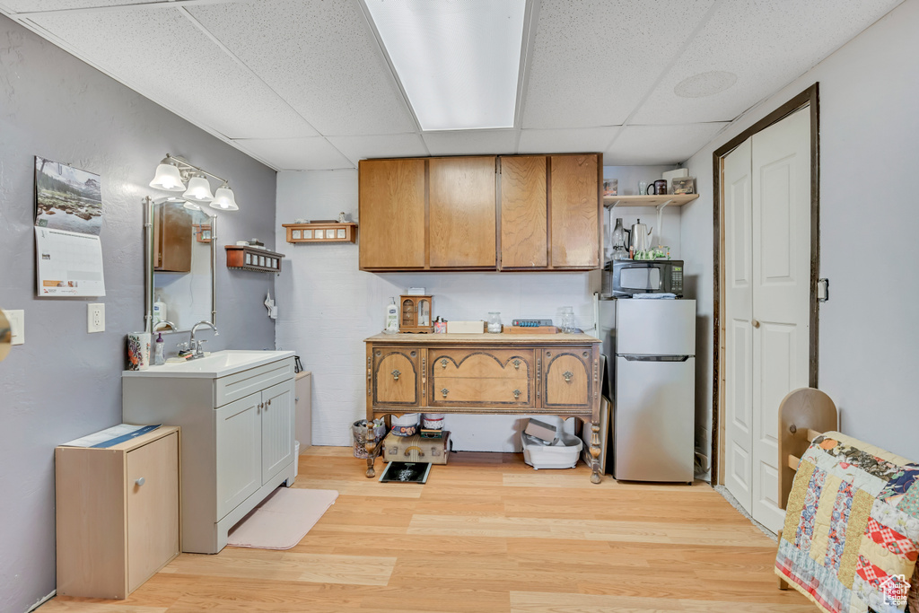 Kitchen with freestanding refrigerator, open shelves, a paneled ceiling, light wood finished floors, and black microwave