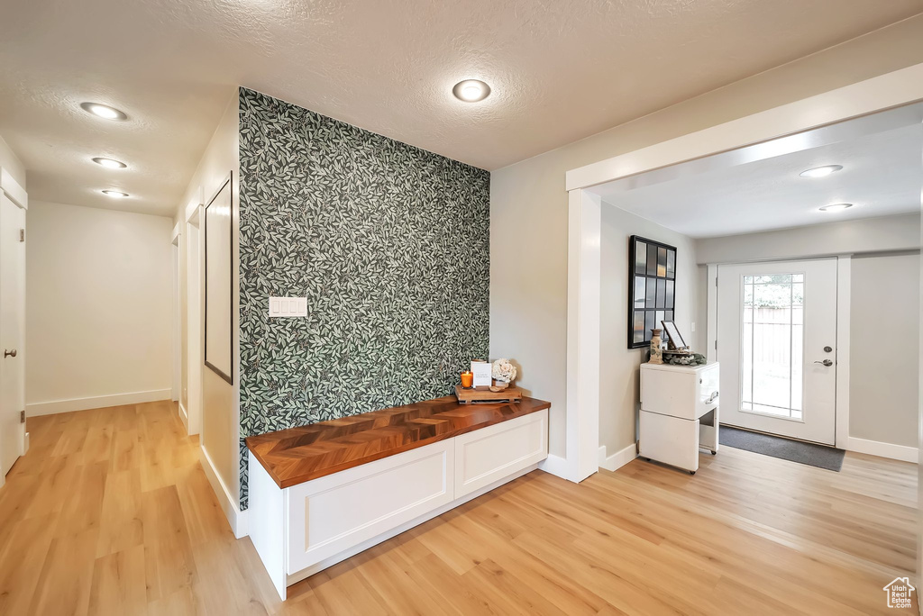 Mudroom featuring wallpapered walls, light wood finished floors, an accent wall, recessed lighting, and a textured ceiling