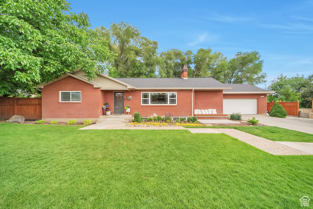 Ranch-style home featuring brick siding, an attached garage, concrete driveway, and a chimney
