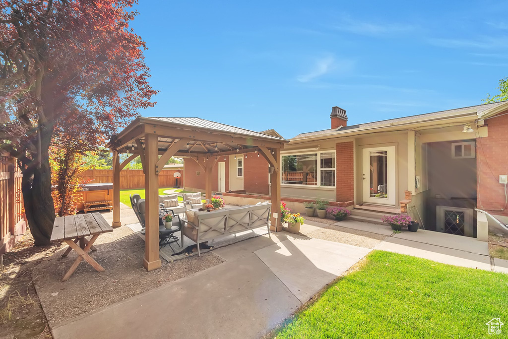 View of patio with a hot tub, a gazebo, and an outdoor hangout area