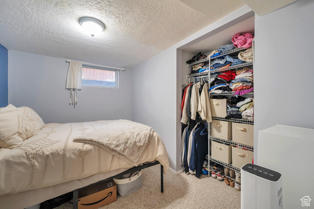 Carpeted bedroom featuring a textured ceiling and a closet