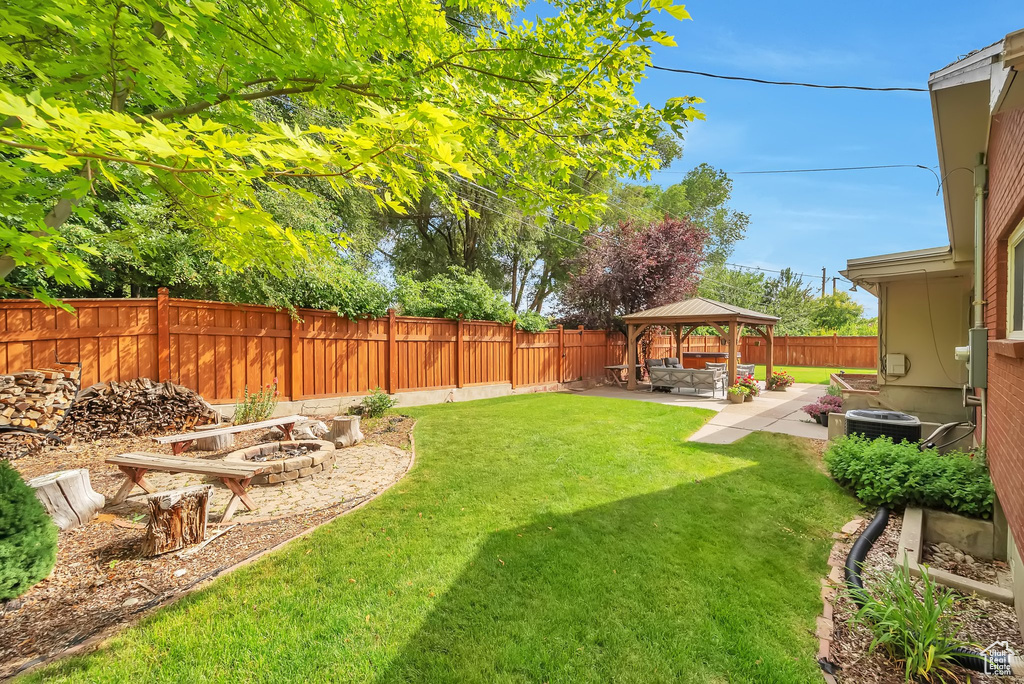 Fenced backyard featuring a gazebo, a patio, and a fire pit