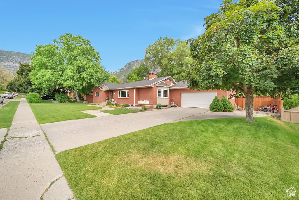 View of front of house with a mountain view, concrete driveway, a chimney, and an attached garage
