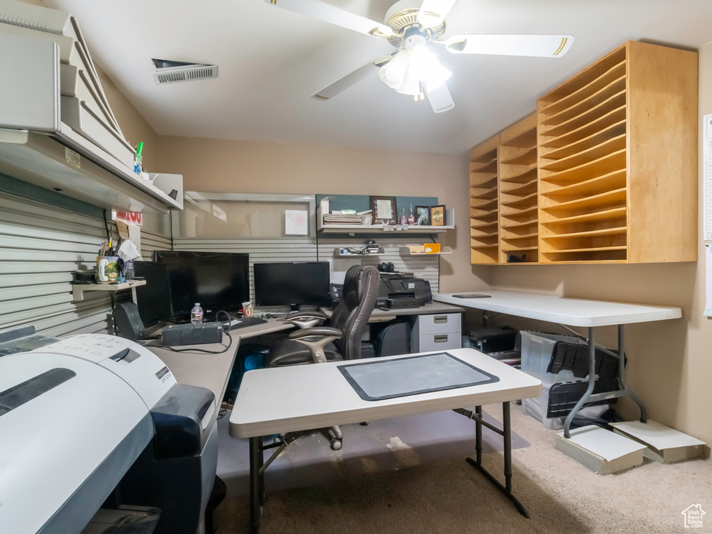 Carpeted office space featuring a ceiling fan