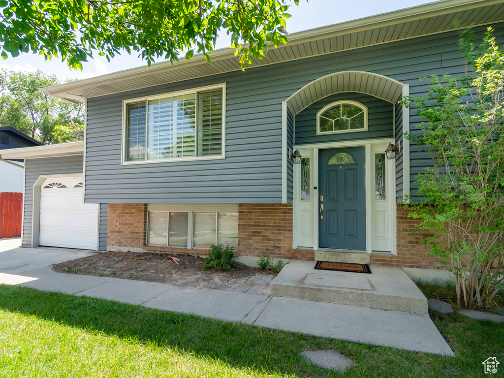 View of front of property with brick siding, an attached garage, and driveway