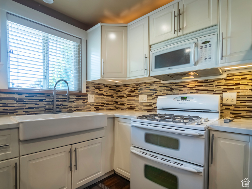 Kitchen featuring white appliances, light countertops, tasteful backsplash, and white cabinetry