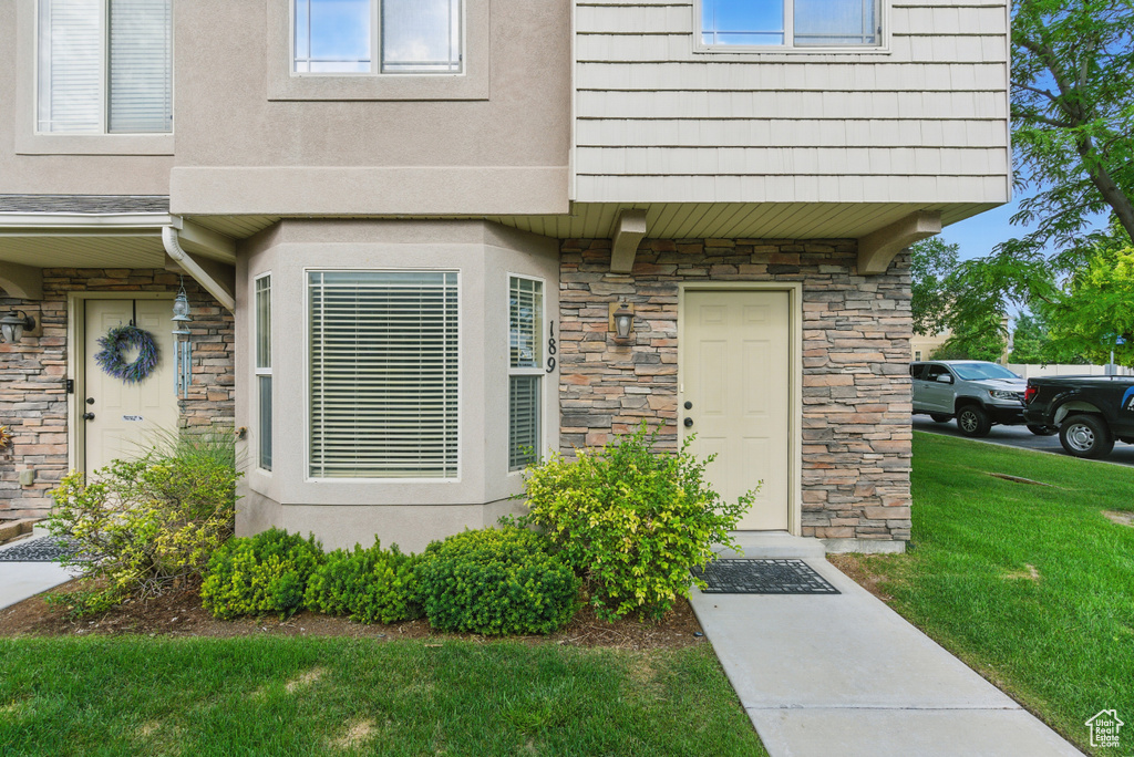 Entrance to property with stone siding and a lawn