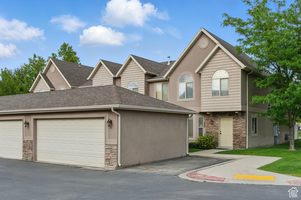 View of front of house featuring stone siding, a shingled roof, stucco siding, and an attached garage
