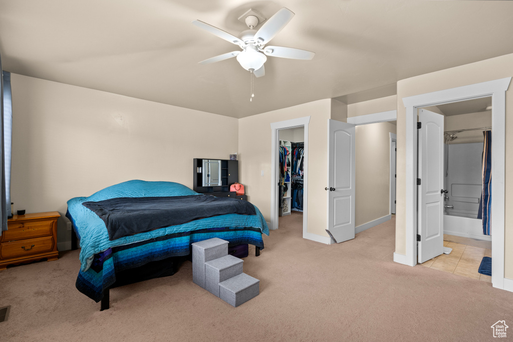 Bedroom with light colored carpet, a spacious closet, a closet, and a ceiling fan