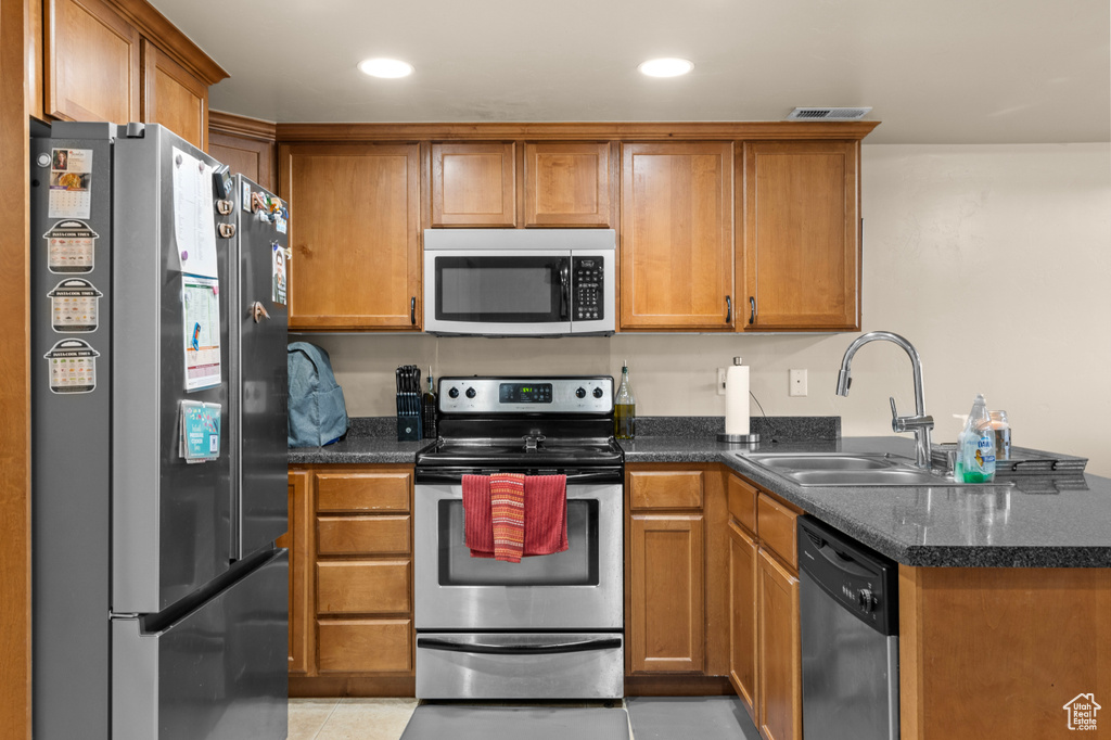 Kitchen featuring stainless steel appliances, a peninsula, brown cabinets, and recessed lighting