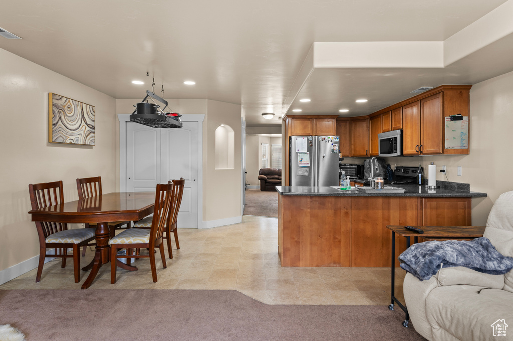 Kitchen featuring appliances with stainless steel finishes, brown cabinets, a peninsula, recessed lighting, and open floor plan