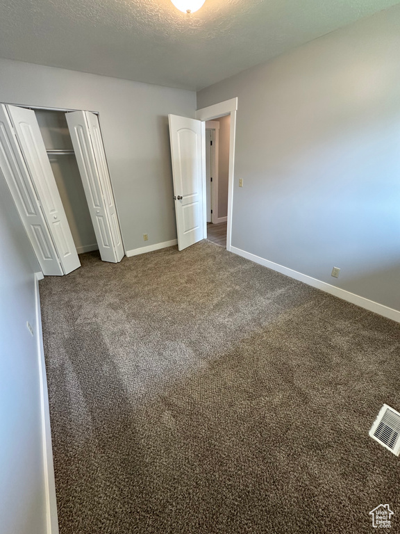 Unfurnished bedroom with carpet, a closet, and a textured ceiling