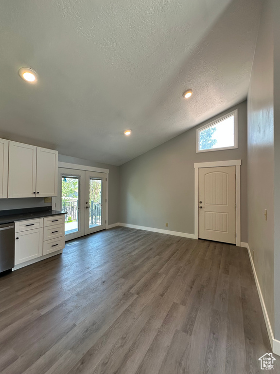 Unfurnished living room featuring french doors, a textured ceiling, vaulted ceiling, wood finished floors, and recessed lighting