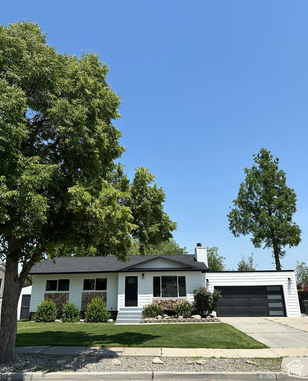 Ranch-style house with a garage, concrete driveway, a front yard, a chimney, and entry steps