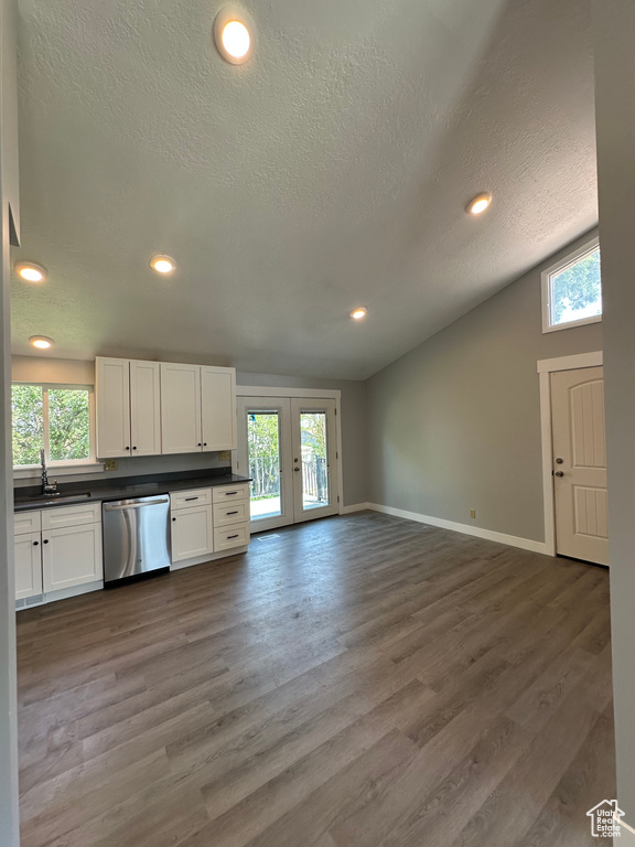 Kitchen with stainless steel dishwasher, dark countertops, vaulted ceiling, plenty of natural light, and french doors