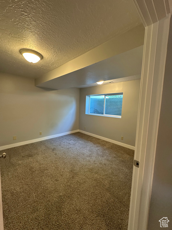 Carpeted empty room with a textured ceiling and baseboards