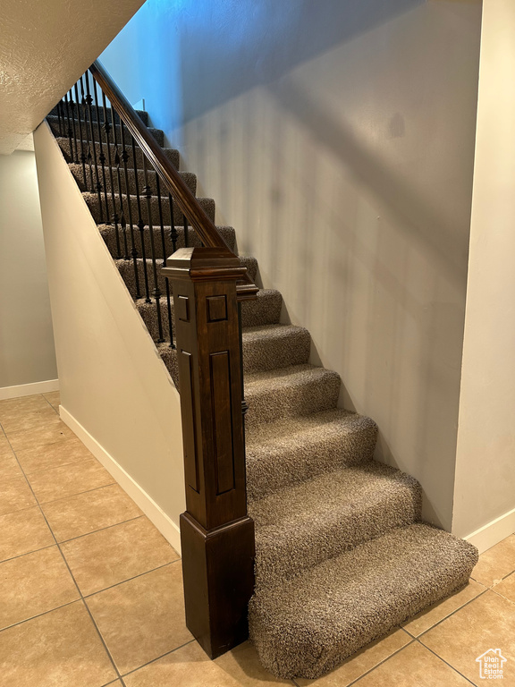 Stairs with tile patterned flooring and baseboards