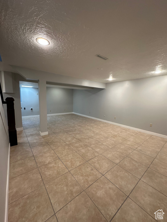 Finished basement featuring a textured ceiling and tile patterned floors