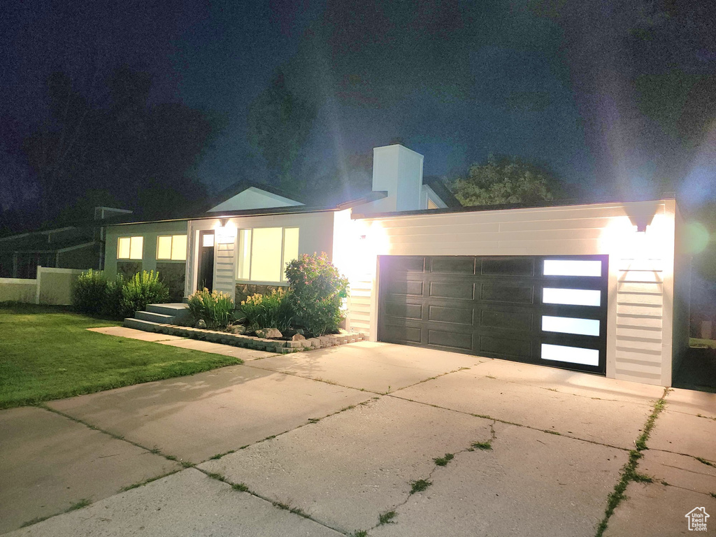 View of front of home featuring driveway, a yard, a garage, and stucco siding