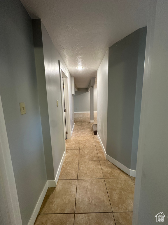 Hall featuring a textured ceiling and light tile patterned floors