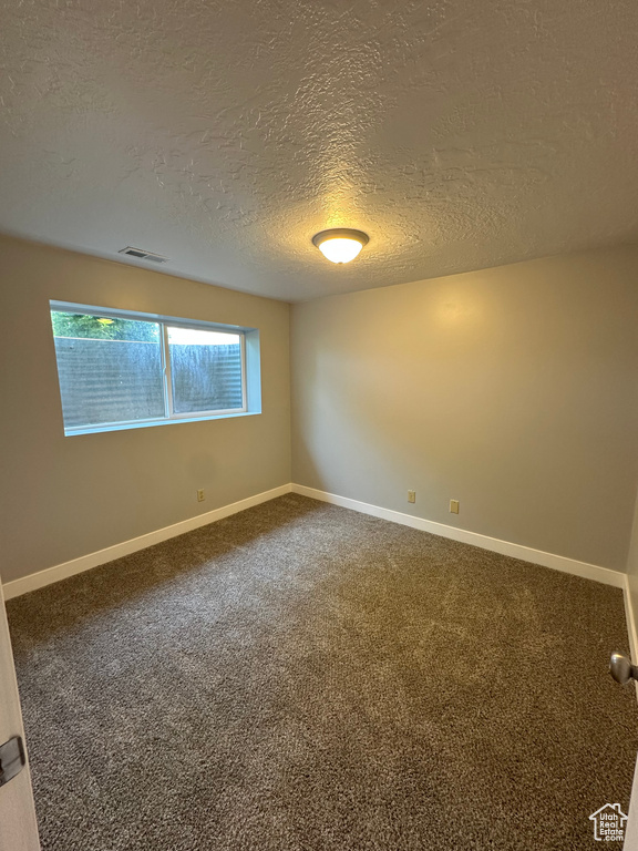 Empty room with a textured ceiling and carpet floors