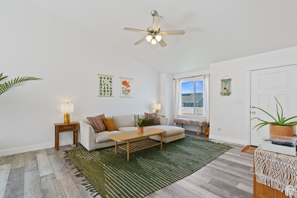Living room with wood finished floors, ceiling fan, lofted ceiling, and baseboards