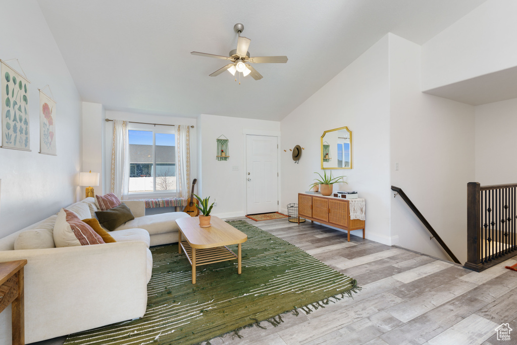 Living room with vaulted ceiling, a ceiling fan, wood finished floors, and baseboards