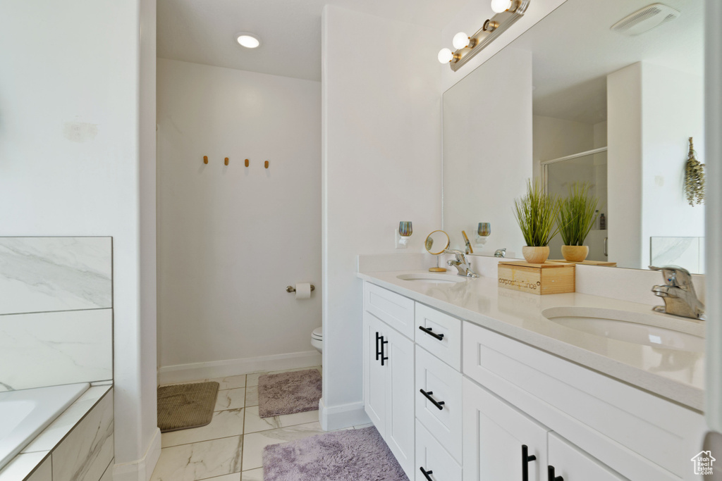 Full bath with double vanity, marble finish flooring, a shower with shower door, toilet, and a bath