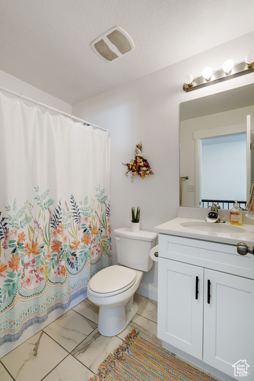 Full bathroom featuring toilet, vanity, marble look tile flooring, curtained shower, and a textured ceiling