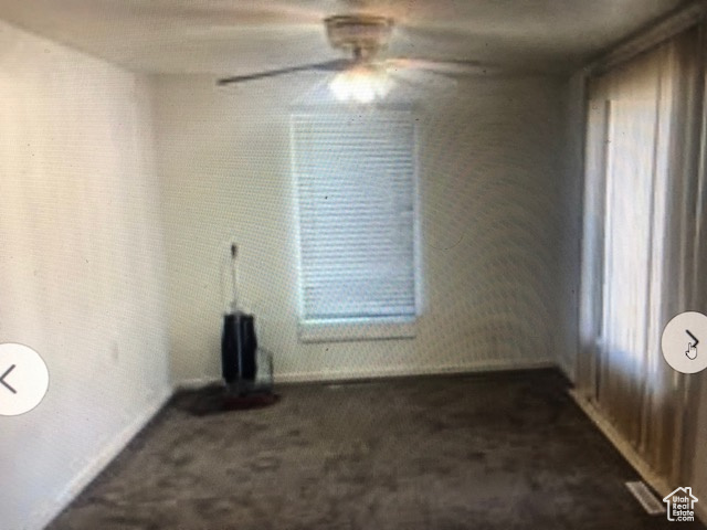 Unfurnished living room with dark colored carpet and ceiling fan