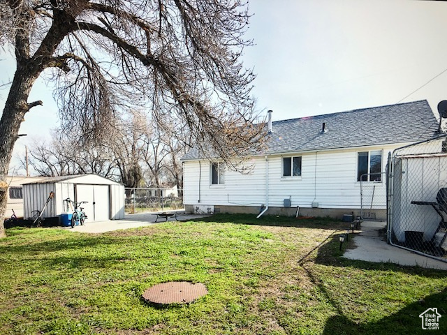 View of green lawn featuring a storage unit and a patio