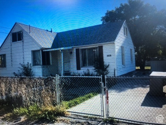 View of front of house with a gate and a shingled roof