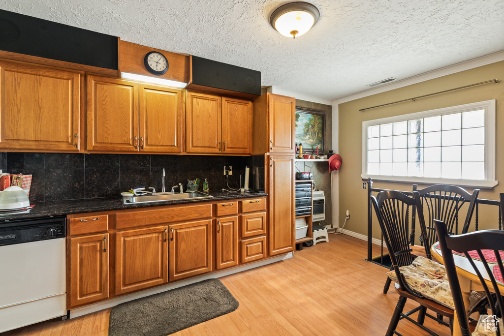Kitchen with dishwasher, decorative backsplash, brown cabinetry, a textured ceiling, and light wood-style flooring
