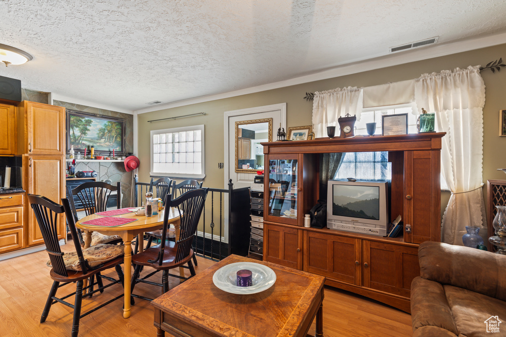 Living room with a textured ceiling, light wood finished floors, and ornamental molding