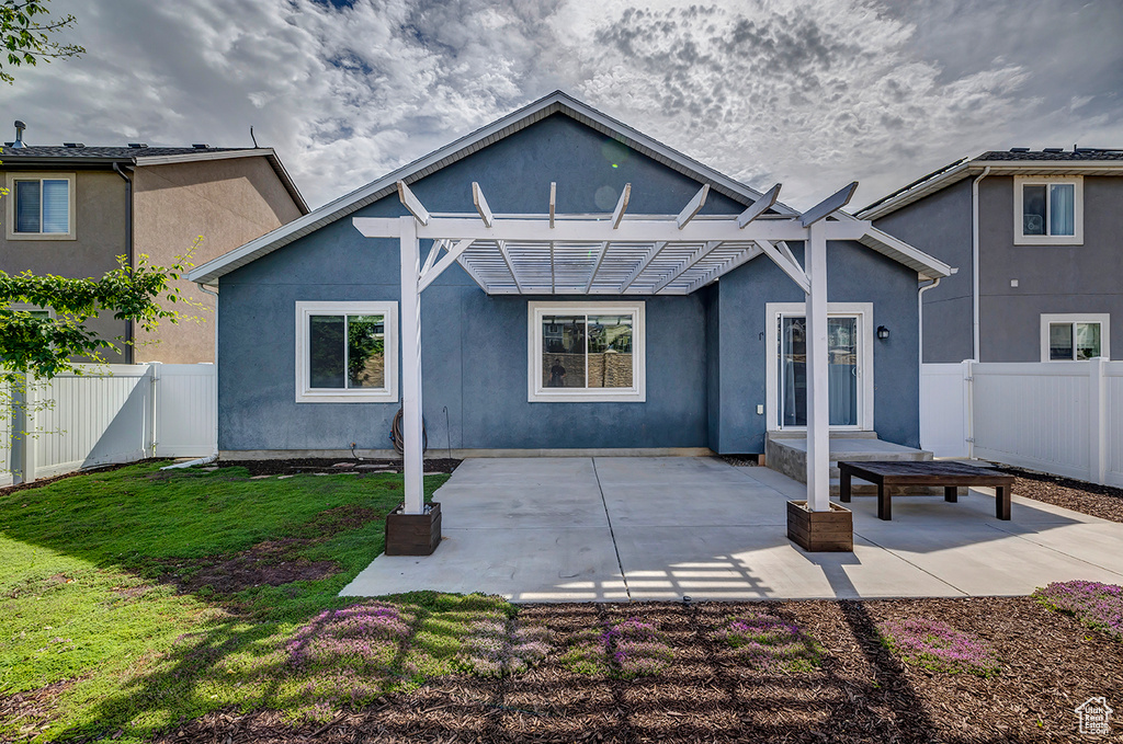 Rear view of house featuring a fenced backyard, a pergola, stucco siding, and a patio