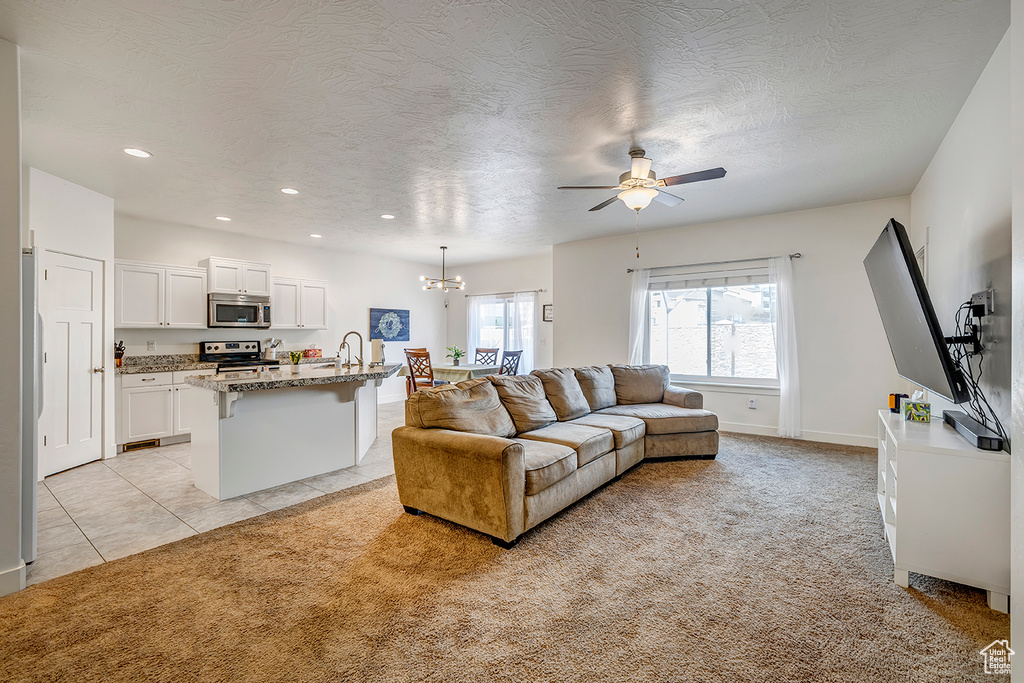 Living area with a ceiling fan, light colored carpet, recessed lighting, a chandelier, and a textured ceiling