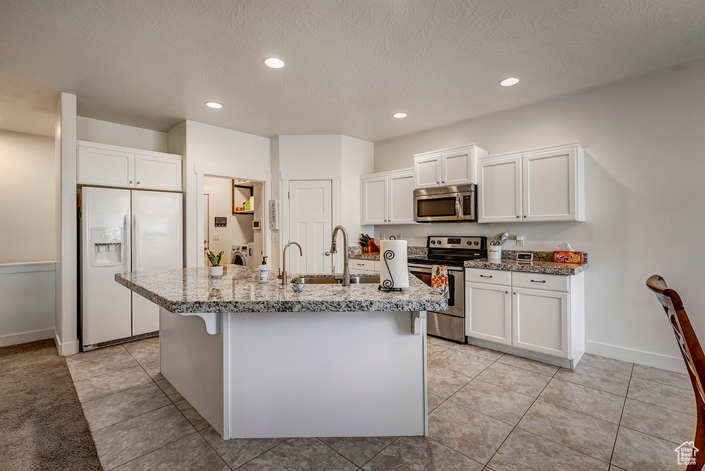 Kitchen featuring stainless steel appliances, white cabinetry, light stone counters, recessed lighting, and a textured ceiling