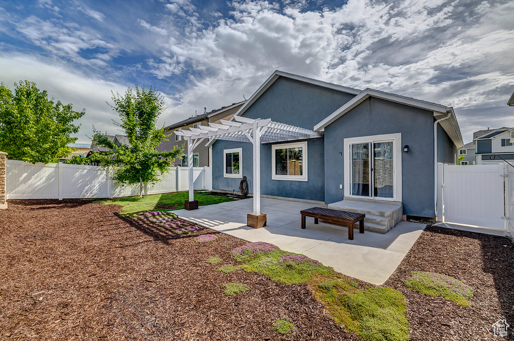Rear view of property with a pergola, stucco siding, a fenced backyard, and a patio area