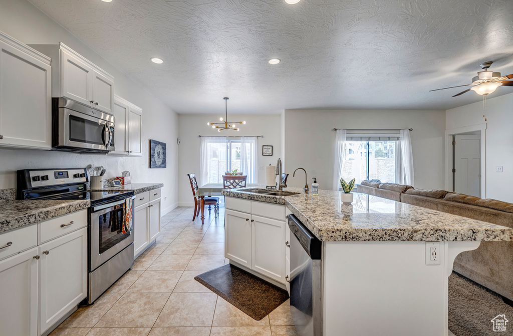 Kitchen featuring stainless steel appliances, open floor plan, a chandelier, recessed lighting, and a kitchen island with sink