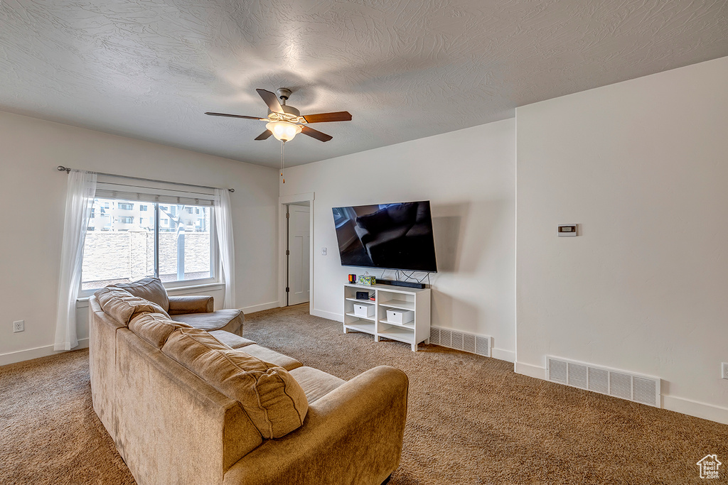 Living room with carpet, a ceiling fan, and a textured ceiling